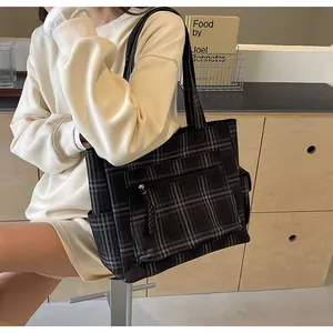 Detail of the black checkered tote bag featuring a front zipper pocket and side pouch