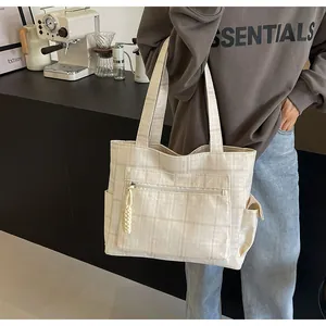 Detail of beige plaid canvas tote bag with front zipper pocket in a lifestyle cafe setting