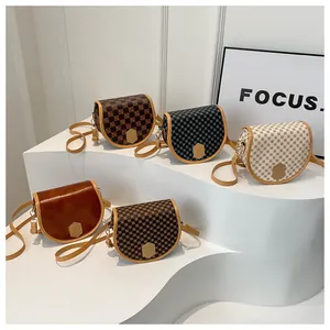 Five vintage saddle bags in various prints and textures displayed on white platforms