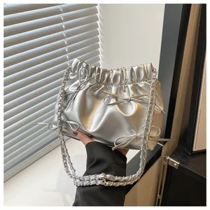 Detailansicht der silbernen Metallic-Eimertasche mit Schleifen und Kettenriemen-Details