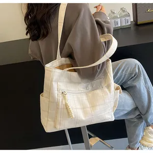 Close-up detail of beige checkered canvas tote bag with front zipper and side pocket