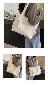 Detail view of large canvas tote bag with classic plaid pattern and side pockets