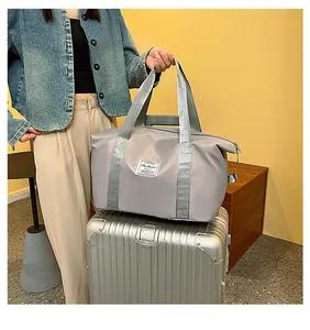 Detail view of a large grey nylon travel bag resting on a silver suitcase handle