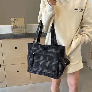 Large plaid canvas tote bag with front zipper pocket shown in a lifestyle indoor setting