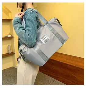 Close-up of lightweight grey waterproof travel bag with fashion label on shoulder
