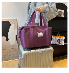 Detail of purple waterproof travel bag showing fashion label and dual handle reinforcement