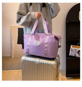 Close-up of purple waterproof nylon travel bag with logo patch on a silver suitcase