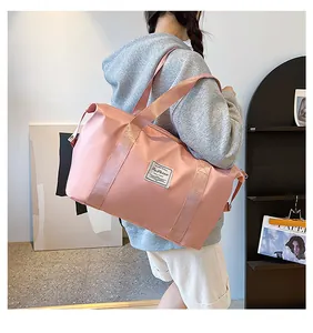 Detailed view of a pink large-capacity waterproof travel bag with embroidery in a lifestyle setting