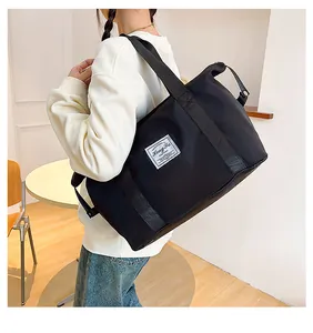 Close-up of black waterproof nylon travel bag with branded patch and wide strap