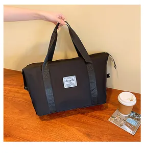 Detail of black high-capacity travel bag with white logo patch and sturdy nylon handles