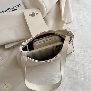 Interior view of minimalist cream underarm bag showing capacity for phone and wallet
