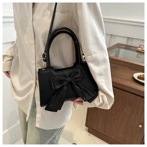 Dettaglio borsa a mano nera con grande fiocco e tracolla stile fatato chic