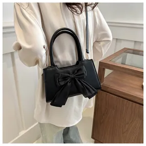 Dettaglio della finitura in pelle PU nera lucida e del grande fiocco decorativo sulla borsa