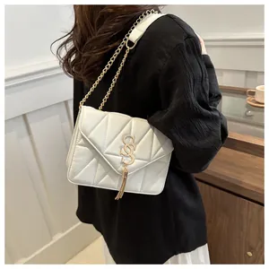 Détail du sac matelassé blanc avec logo S doré et pompon à franges élégant