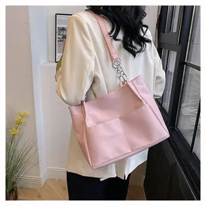 Pink PU leather tote bag with chain strap and double front pockets on female model