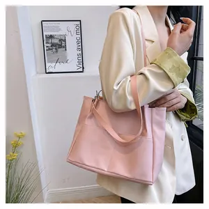 Detail of soft pink large capacity tote bag worn on shoulder by professional model