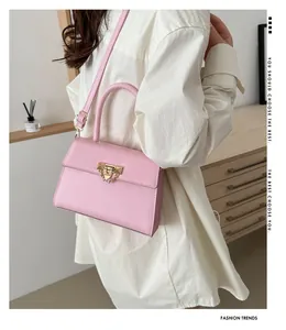Detail of light pink crossbody bag with gold hardware and chain strap on a model