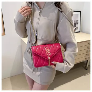 Détail du sac bandoulière matelassé rose rouge avec chaîne dorée et pompon métallique