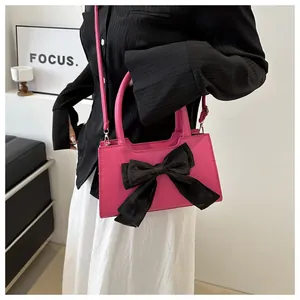 Dettaglio della borsa a tracolla rosa con un grande fiocco decorativo in velluto nero