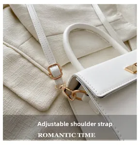 Detail showing adjustable shoulder strap and golden metal hardware on white handbag
