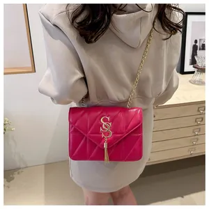 Détail du sac bandoulière fuchsia matelassé avec logo SS doré et pompon élégant