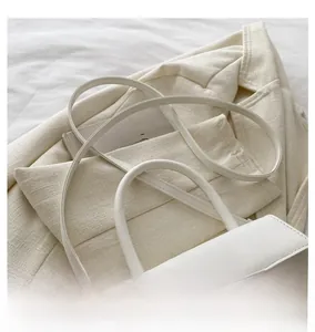 Detail showing the minimalist white crossbody bag with gold hardware on a cream blazer