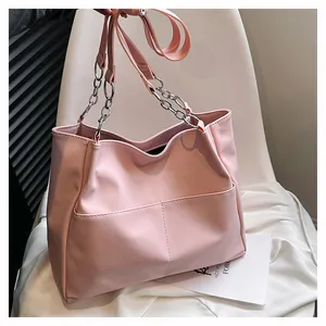 Detail of light pink faux leather tote bag with chain strap and dual front pockets