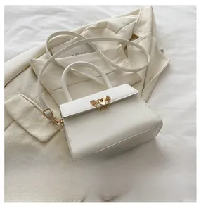 Detailed view of a white PU leather crossbody bag with gold hardware and phone for scale