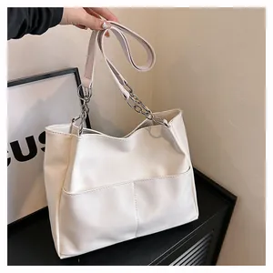 Detail view of white PU leather tote bag featuring metal chain and side pockets