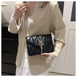 Détail d'un sac bandoulière matelassé noir avec chaîne dorée et gland en métal