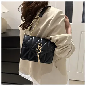 Détail d'un sac bandoulière noir matelassé avec chaîne dorée et pompon sur un mannequin