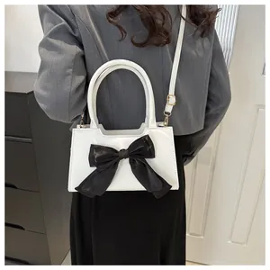 Dettaglio borsa a mano bianca con grande fiocco nero e tracolla versatile