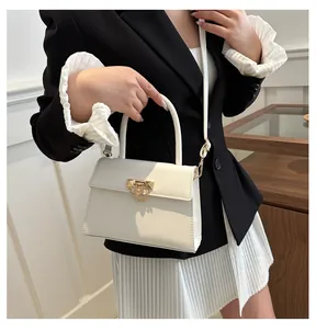 Detail view of cream faux leather crossbody bag with gold rivet buckle and chain decor