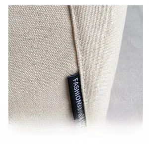 Detailed macro view of beige canvas fabric with a black Fashion label on the side seam