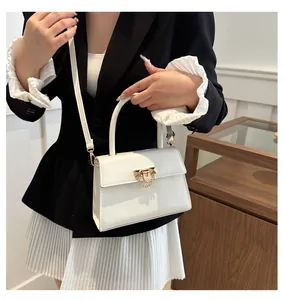 Detail of pearl white crossbody bag with golden rivet lock and chain decoration