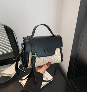 Detailansicht der gewebten Stroh-Handtasche mit schwarzem Leder und Rundschließe