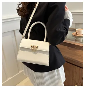 Detail view of a white leather square bag with gold metal lock and chain strap on a model
