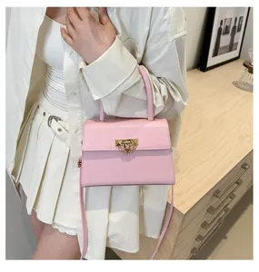 Detail of pink faux leather crossbody bag with golden chain buckle on a soft white outfit