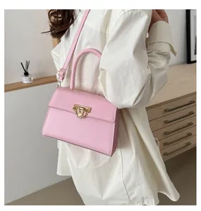 Close-up of pink lychee grain crossbody bag featuring gold metal lock and chain details