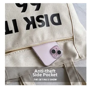 Detail of the anti-theft side zipper pocket on a beige canvas tote bag with a smartphone