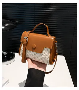 Detailaufnahme der braunen Leder-Stroh-Handtasche mit Metallverschluss und Tragegriff