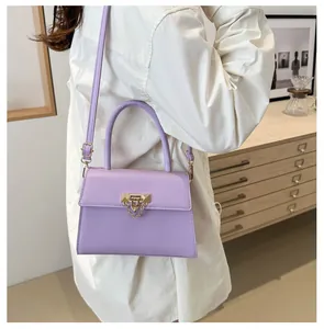 Lavender square handbag with gold metal clasp worn with white shirt in a modern room