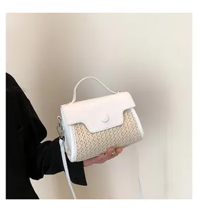 Detail einer Strohhandtasche mit weißer Lederklappe und verstellbarem Riemen