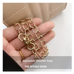 Close-up of golden metal chain strap with lobster clasp on beige quilted leather bag