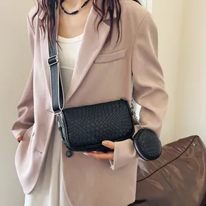 Detail of black woven shoulder bag featuring a wide strap and a matching round coin purse