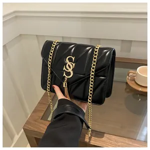 Détail du sac bandoulière noir matelassé avec logo doré, gland et bandoulière chaîne