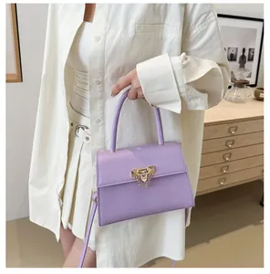 Close-up of lavender purple crossbody bag with golden metal lock and chain detail