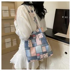 Detail of patchwork canvas tote bag featuring denim and plaid textures on a model's shoulder
