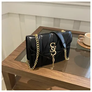 Détails d'un sac à bandoulière noir matelassé avec logo doré et pampille métallique