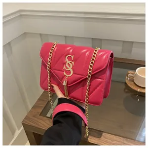 Détail du sac en cuir matelassé fuchsia avec logo doré et pompon décoratif